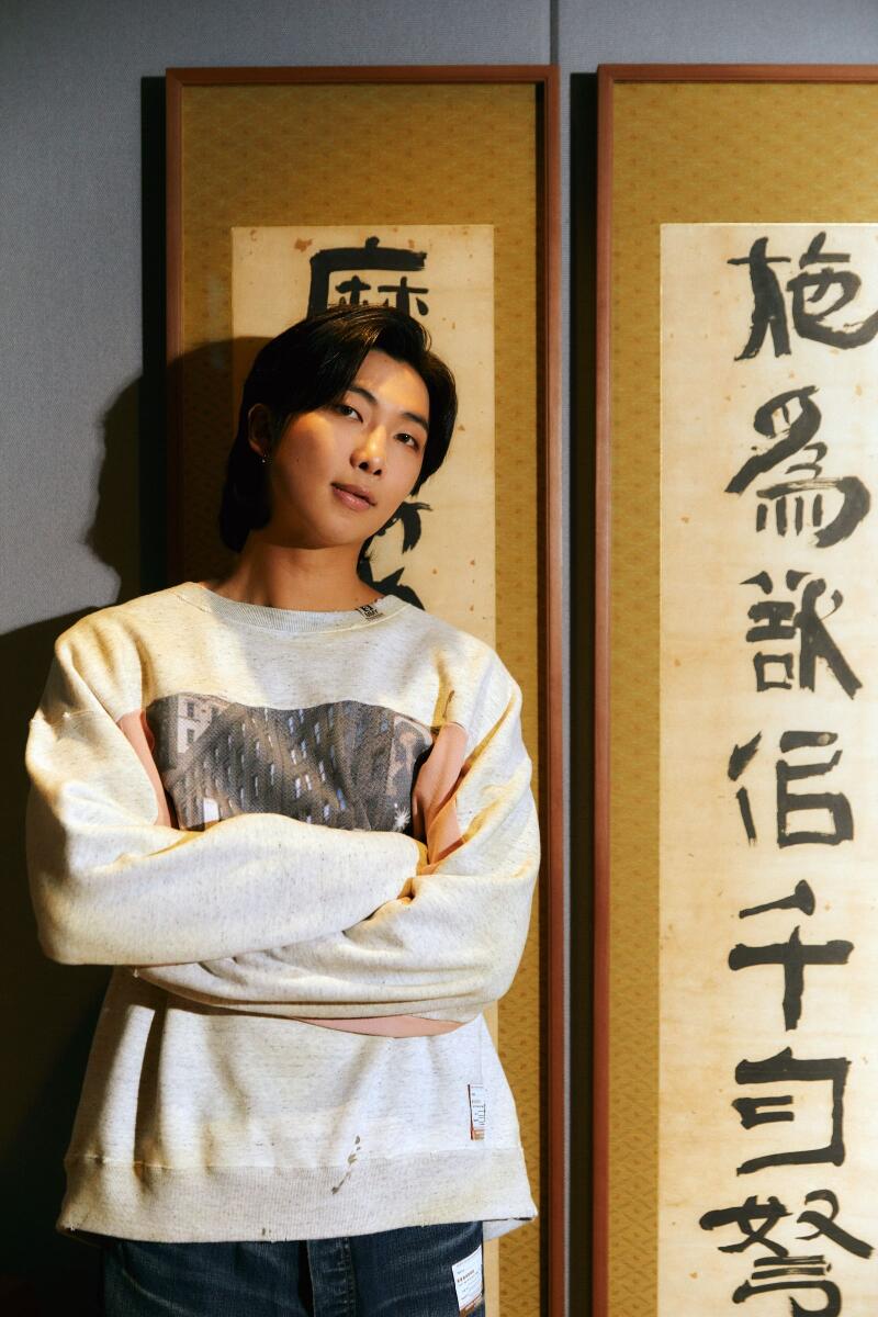 RM, the leader of the South Korean pop group BTS, stands in front of work by the Joseon dynasty-era calligrapher Kim Jeong-hui at his recording studio in Seoul on Aug. 18, 2022. (Dasom Han/The New York Times)
