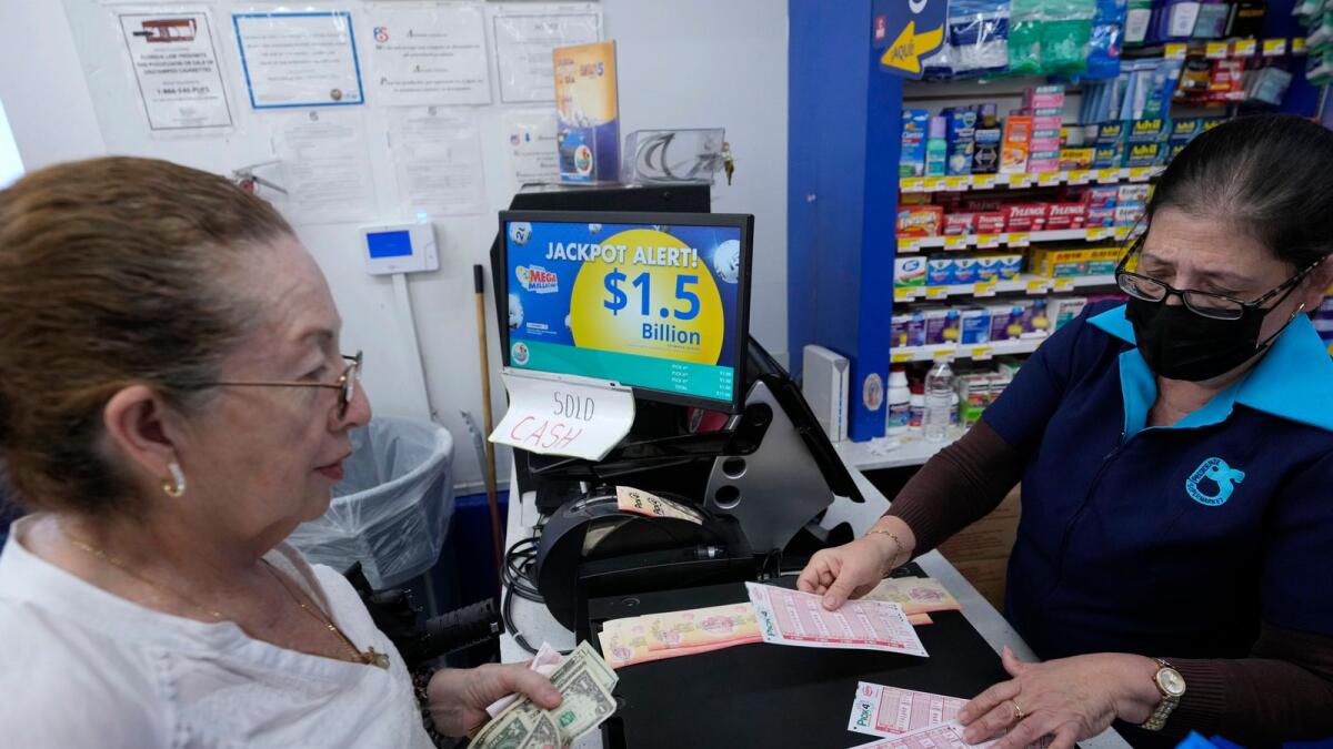 Mirta Herrera, right, sells lottery tickets on Monday at the Presidente Supermarket in the Little Havana neighborhood of Miami. — AP