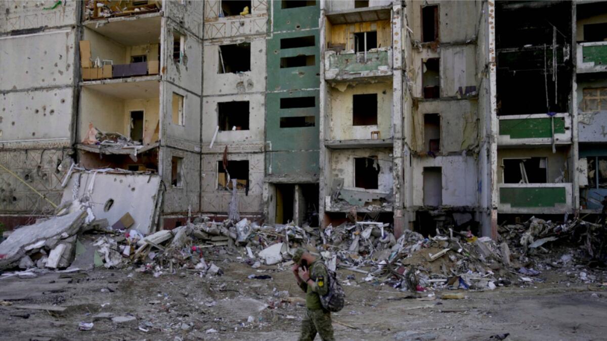 A soldier walks past a building destroyed by attacks in Chernihiv, Ukraine. — AP