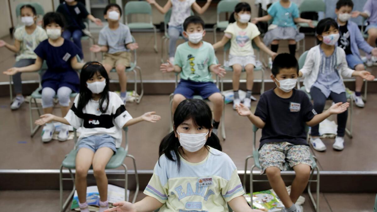 Students wearing protective face masks amid the coronavirus disease (Covid-19) outbreak, clap along instead of singing a song during a music class at Takanedai Daisan elementary school, which practices various methods of social distancing in order to prevent the infection, in Funabashi, east of Tokyo, Japan. Photo:  Reuters