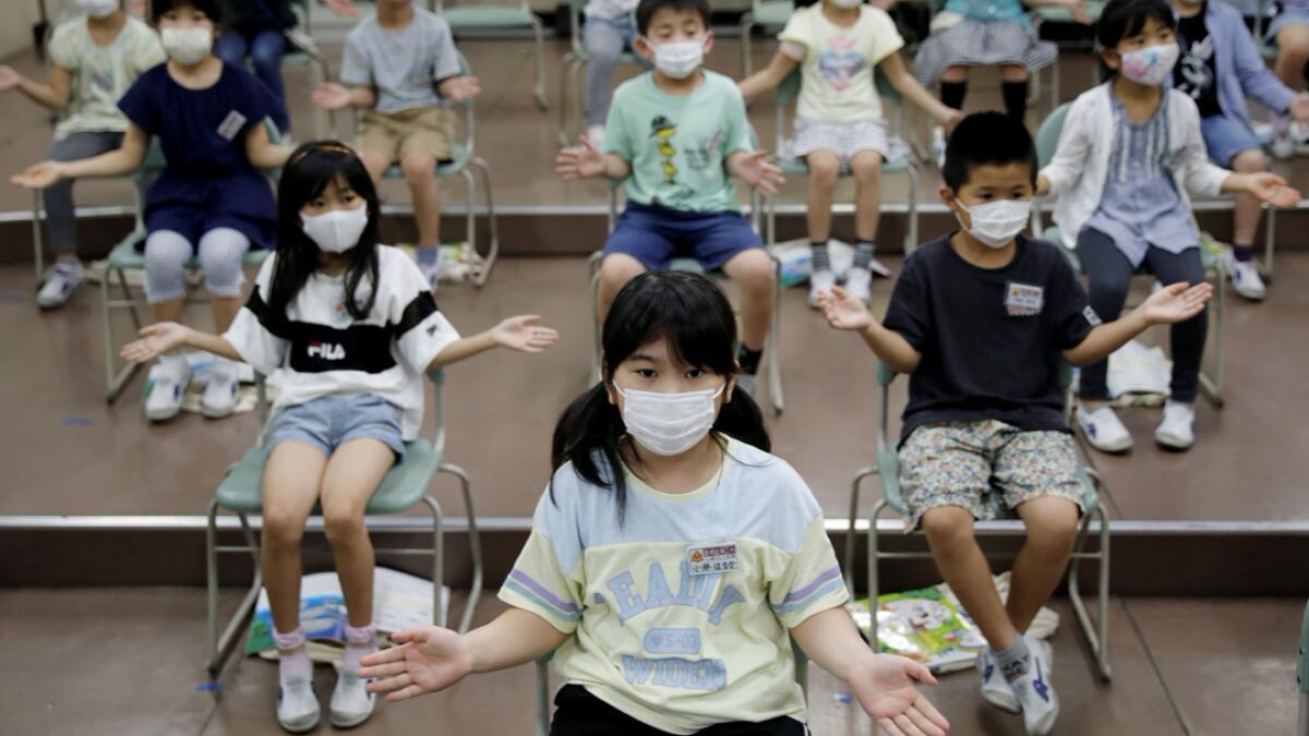 Students wearing protective face masks amid the coronavirus disease (Covid-19) outbreak, clap along instead of singing a song during a music class at Takanedai Daisan elementary school, which practices various methods of social distancing in order to prevent the infection, in Funabashi, east of Tokyo, Japan. Photo:  Reuters