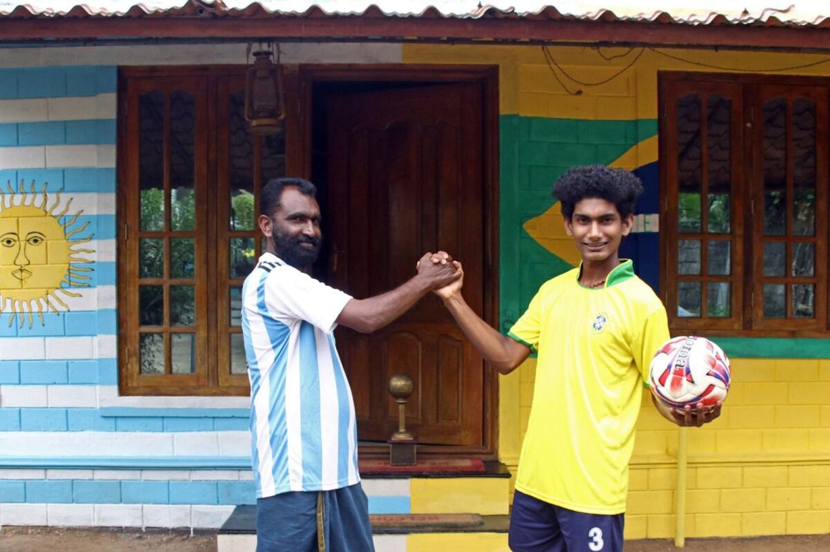 Yeshuda Xavier (left), a fan of Argentina's team and his son Jomon, a fan of Brazilian team, pose for pictures in India. AFP
