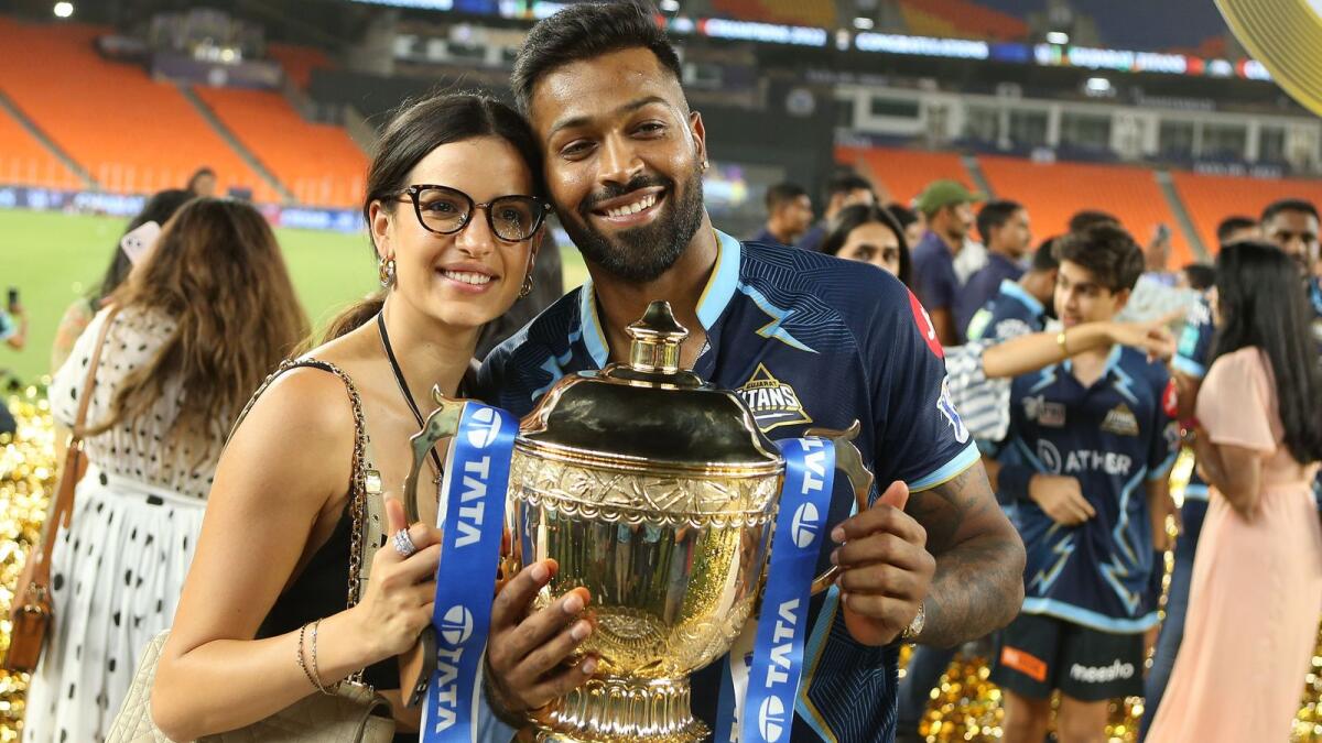 Gujarat Titans captain Hardik Pandya and his wife pose with the trophy after the IPL final on Sunday night. (BCCI)