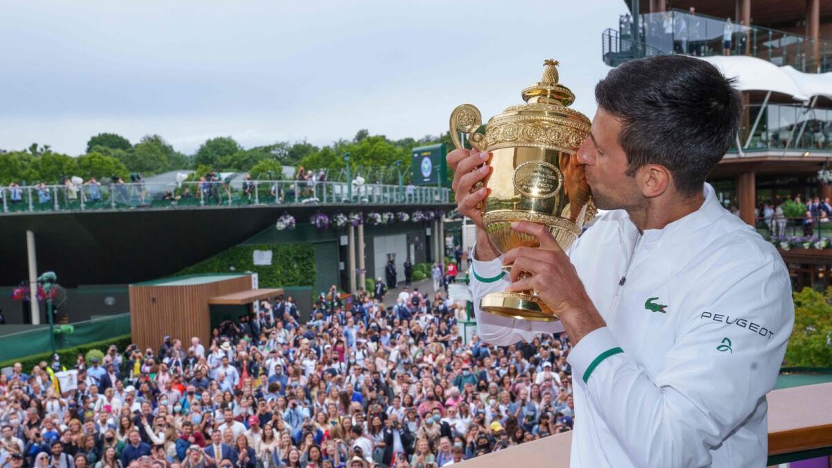 Spectators cheer as Serbia's Novak Djokovic kisses the winner's trophy on the balcony of the Clubhouse after defeating Italy's Matteo Berrettini during their Wimbledon final. — AFP