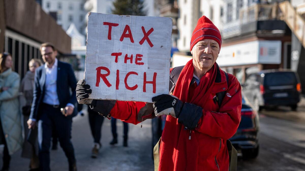Phil White, a British millionaire poses with a placard reading: 'Tax the rich' next to the Congress centre during the World Economic Forum (WEF) annual meeting in Davos on January 18, 2023. — AFP