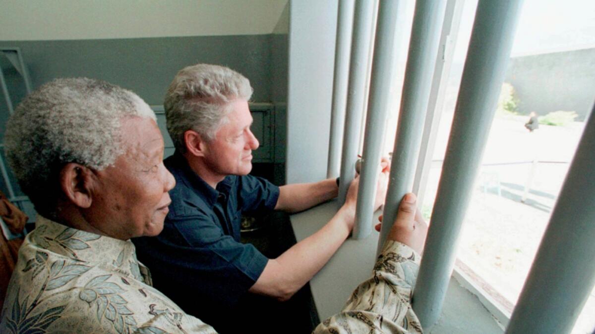 Nelson Mandela and former US president Bill Clinton look to the outside from Mandela's Robben Island prison cell in Cape Town, South Africa. — AP file