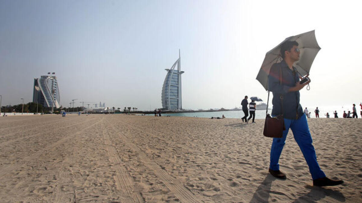 A tourist protects himself from the heat while walking at the Jumeirah Open Beach near the Burj Al Arab, Dubai. Photo Dhes Handumon/ Khaleej Times