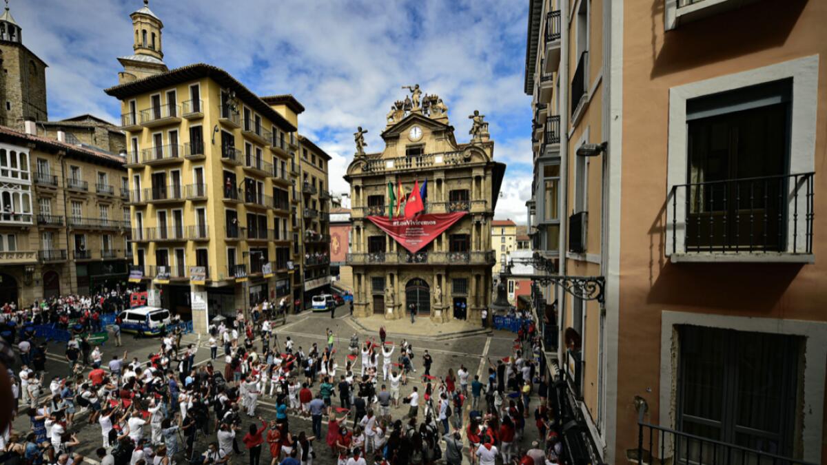 Residents, wearing white clothes and traditional red scarves, take to the streets on the day the ''txupinazo'' would usually take place to start the famous San Fermin festival, which was due canceled this year by the conoravirus, in Pamplona, northern Spain. Photo: AP