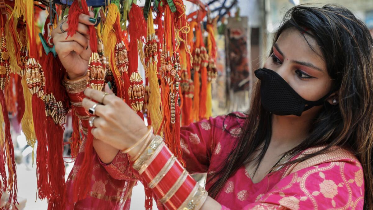 A young woman purchases 'rakhi' ahead of Raksha Bandhan festival, in Jammu. Photo: PTI