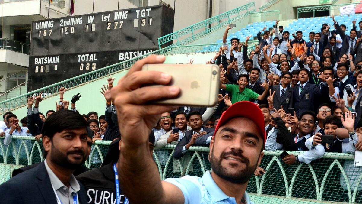 Afghanistan's Rashid Khan (right) takes a selfie with fans during the third day of the only Test match between Afghanistan and West Indies in Lucknow, India, on November 29, 2019. (AFP file)