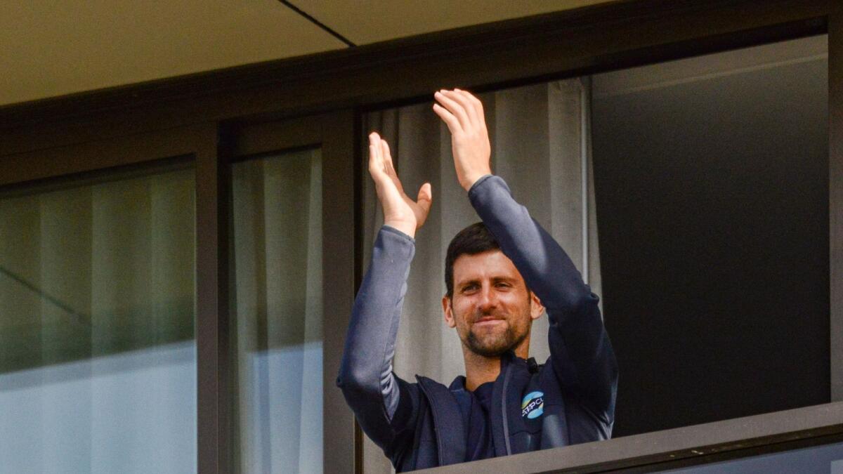 Novak Djokovic gestures from his hotel balcony on the last day of his two-week quarantine in Adelaide on Thursday. (AFP)