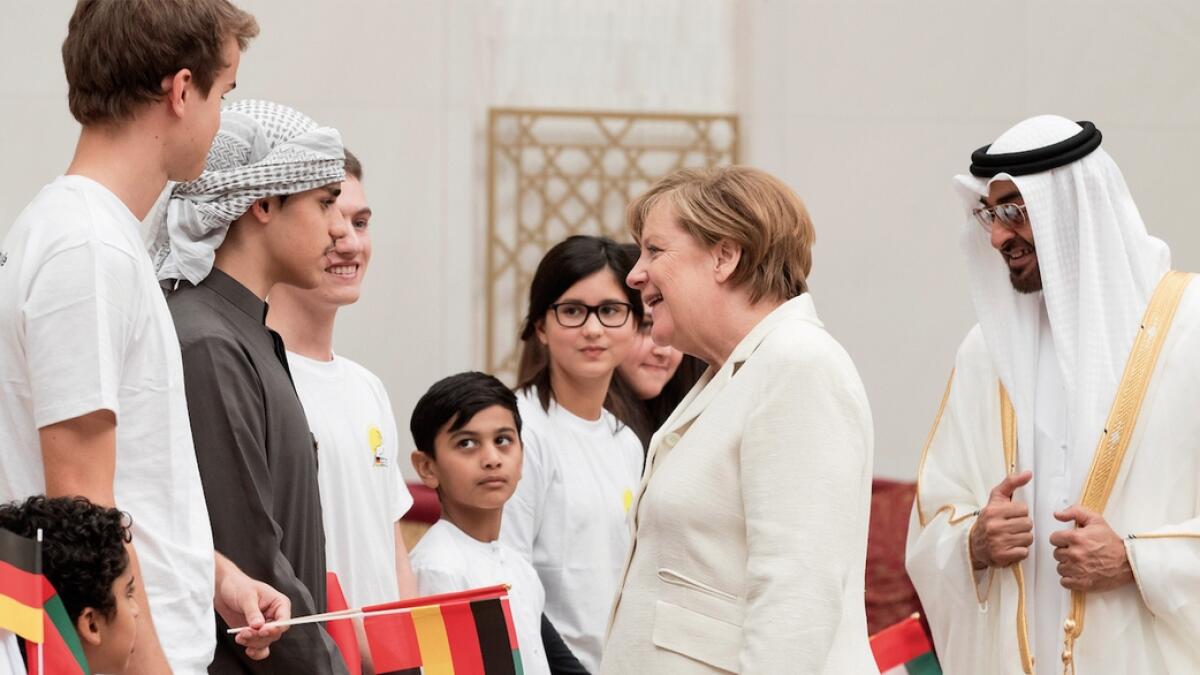 Sheikh Mohamed looks on as German Chancellor Angela Merkel talks to a student from German International School