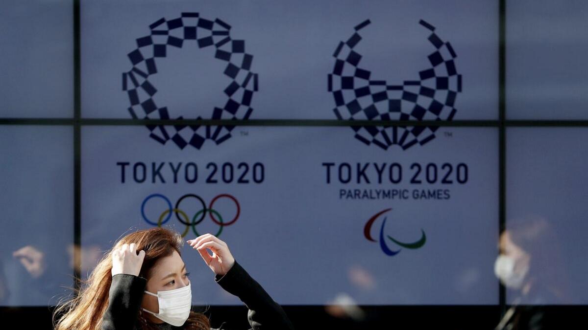 A passerby, wearing a protective face mask, following an outbreak of the coronavirus disease, walks past a screen displaying logos of Tokyo 2020 Olympic and Paralympic Games in Tokyo, Japan, in March. - Reuters file