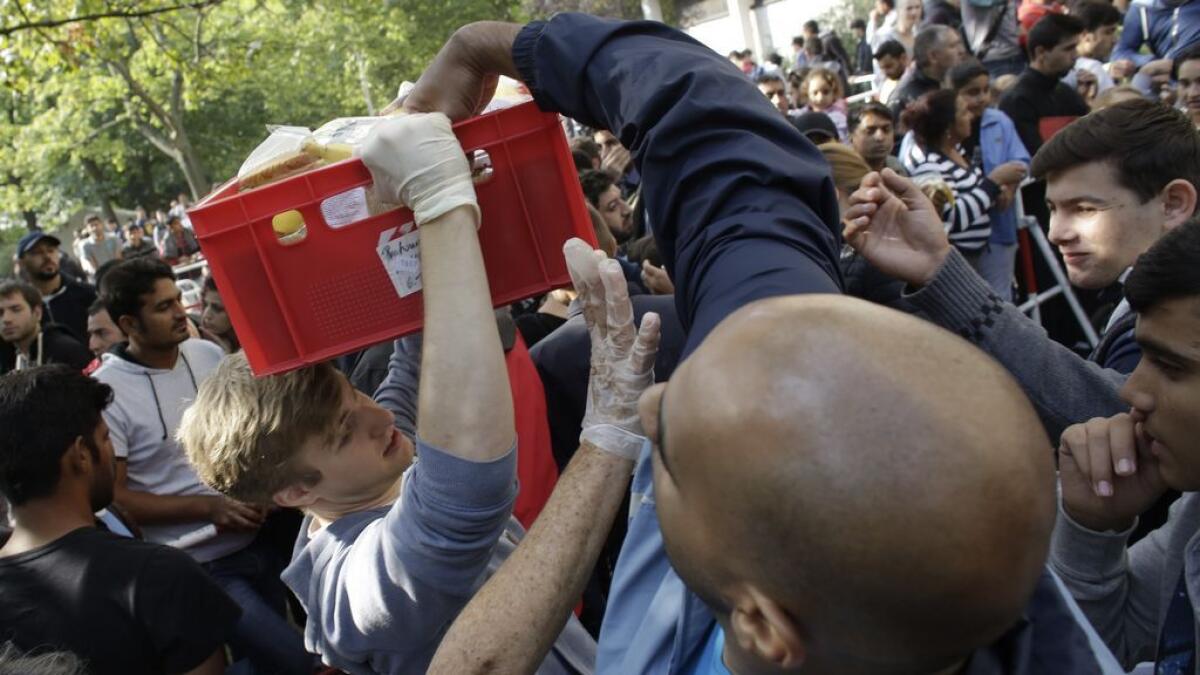 Migrants grab for food delivered by volunteers as they wait for registration at the reception center for refugees and asylum seekers in Berlin.