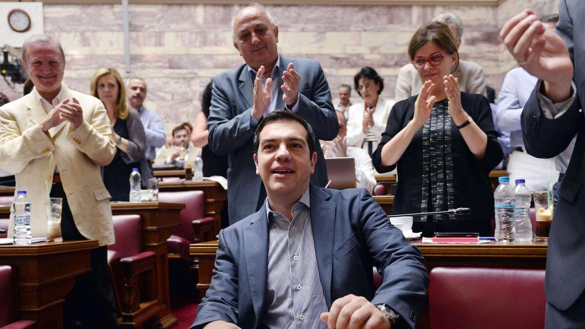 Greek prime minister Alexis Tsipras is applauded by lawmakers before addressing his parliamentary group meeting at the Greek parliament in Athens on Friday. — AFP
