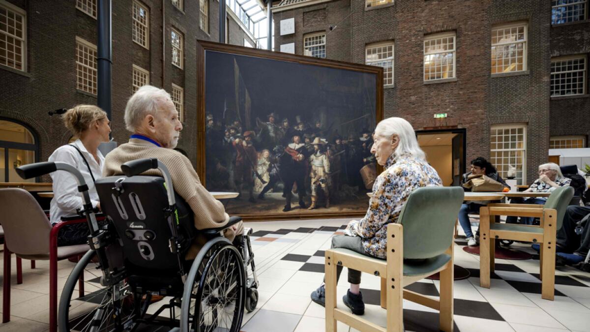 Residents of the Dr. Sarphati House nursing home in Amsterdam, The Netherlands, sit in front of a same size version of the famous painting 'The Night Watch' by Dutch painter Rembrandt van Rijn, in Amsterdam. This summer, the Rijksmuseum brings a version of the world-famous painting by Rembrandt to thirty nursing and care homes and senior complexes. Outings to cultural institutions are not possible for many elderly people due to the coronavirus crisis. Photo: AFP