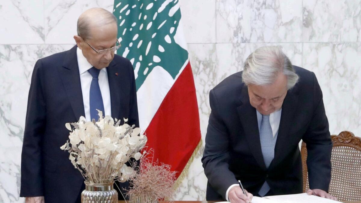 Lebanese President Michel Aoun (L) watches as UN Secretary-General Antonio Guterres signs the visitors book during a visit to the presidential palace in Baabda. — AFP