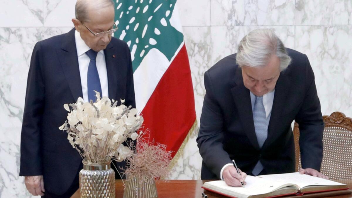 Lebanese President Michel Aoun (L) watches as UN Secretary-General Antonio Guterres signs the visitors book during a visit to the presidential palace in Baabda. — AFP