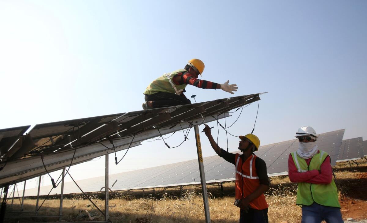 Workers install solar panels at the Pavagada Solar Park 175km north of Bangalore, India, on March 1, 2018. — AP