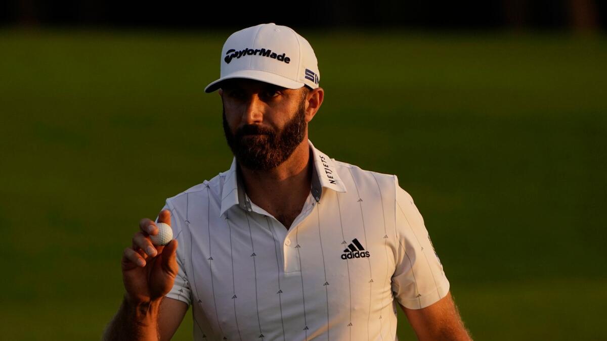 Dustin Johnson holds up his ball on the 18th green after his third round of the Masters golf tournament. — AP