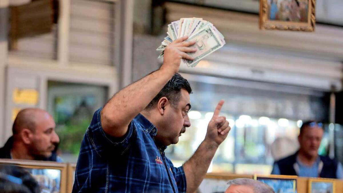A man holds up preserved specimens of various banknotes at the auction at the Moudallal cafe in Baghdad on March. — AFP