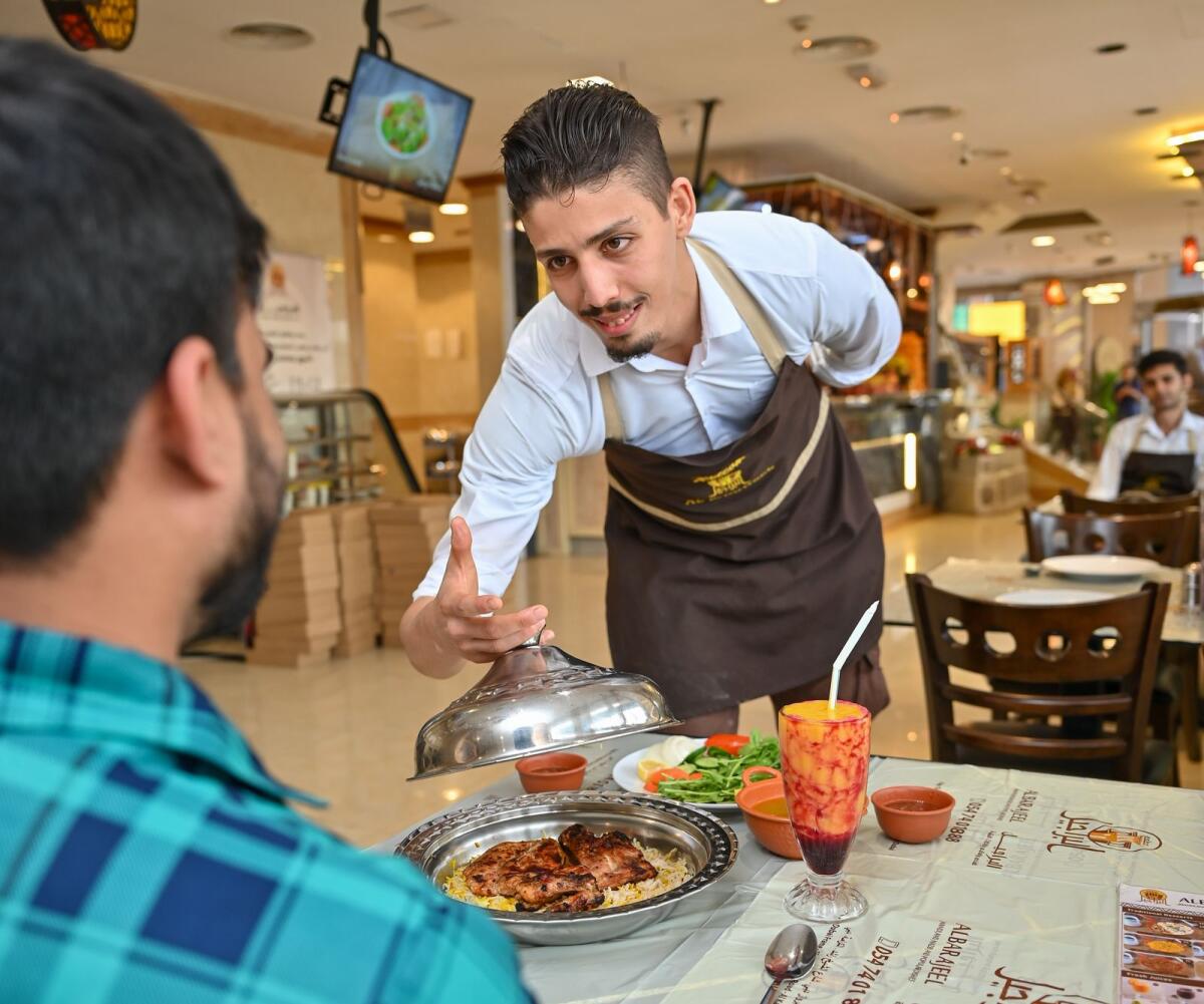 Riedwan Dalfaoui, server at Barajeel Mandi Restaurant in Al Karama, serves food to one of his customers during Ramadan. Photo by Muhammad Sajjad/KT