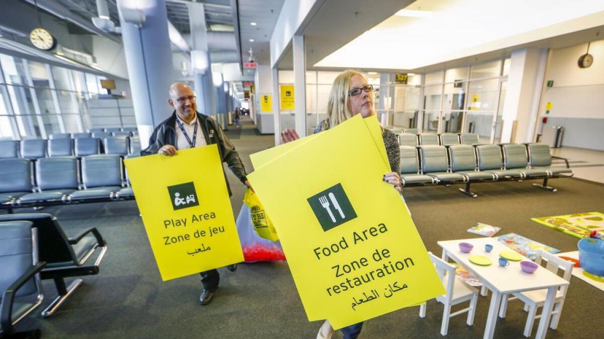 Greater Toronto Airports Authority employees hang signage with English and Arabic translations during a tour of the Infield Terminal at Toronto Pearson International Airport, that is set up as a temporary port-of-entry for Syrian refugees entering Canada in Mississauga