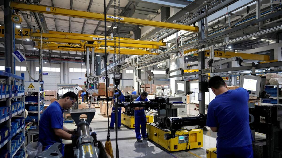 Employees work on the production line of vehicle components at a German factory. In the eurozone, S&amp;P Global’s final manufacturing Purchasing Managers’ Index (PMI) fell to 49.8 in July from June’s 52.1, its first time below the 50 mark separating growth from contraction since June 2020. — File photo