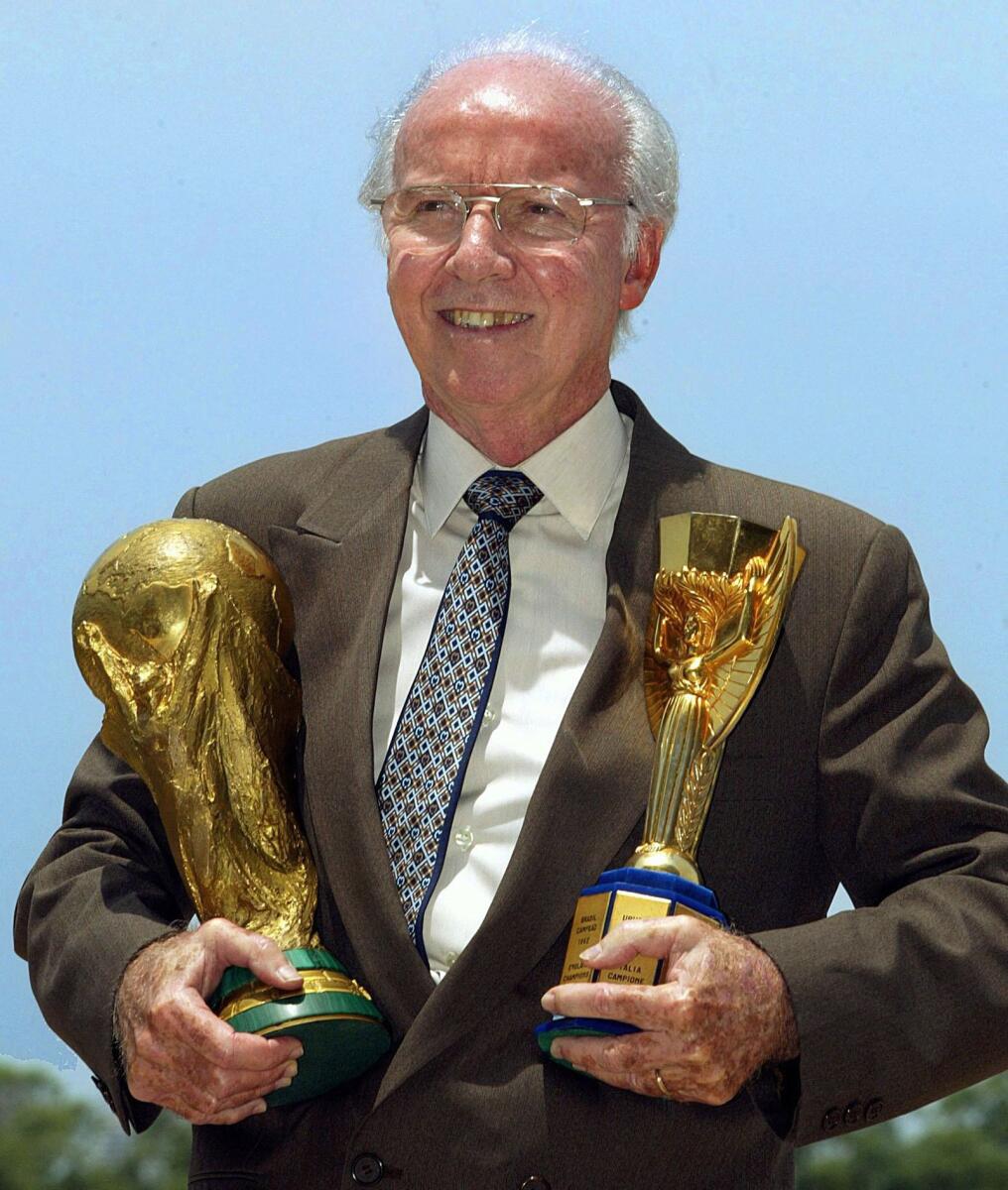 Four-time World Cup winner Mario Zagallo holds the Jules Rimet (R) and FIFA trophies as he poses for photographers in Rio de Janeiro, Brazil in March 2003. = AFP