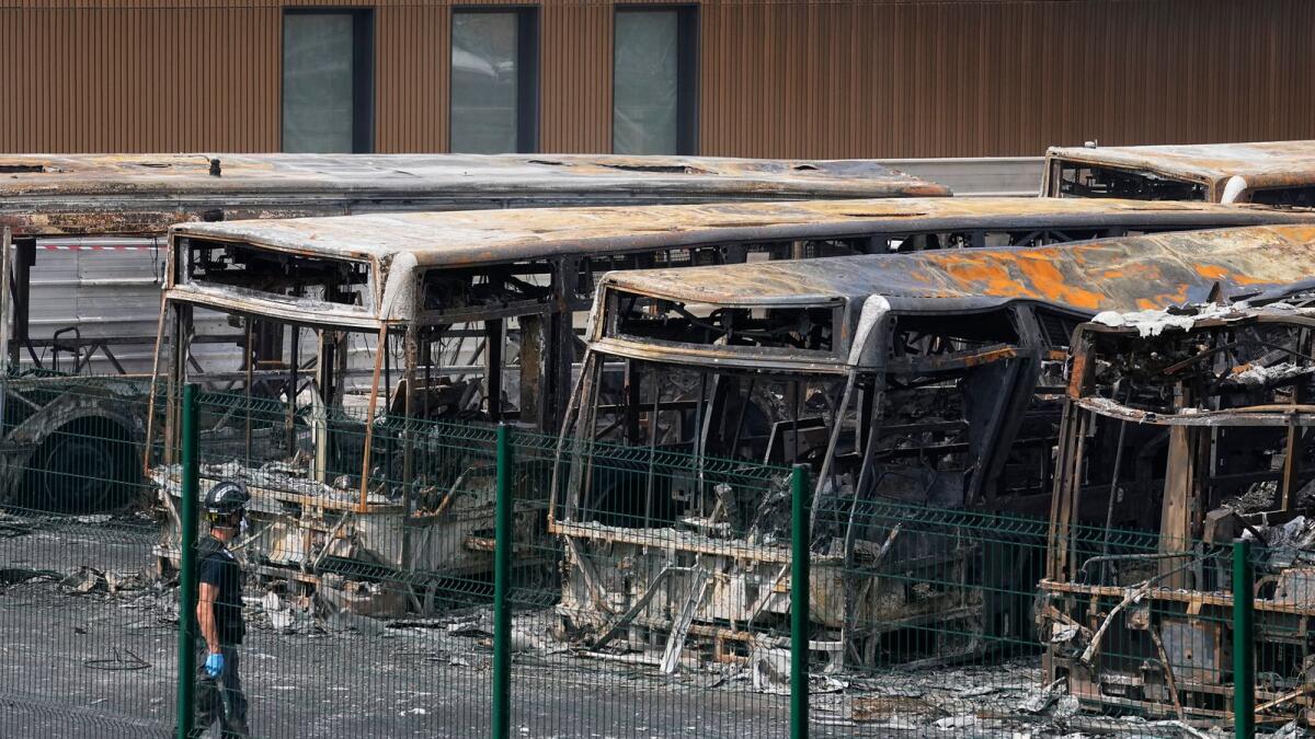 A police investigator watches charred buses on a third night of unrest, Friday, June 30, 2023 at the bus depot of Aubervilliers, outside Paris. — AP