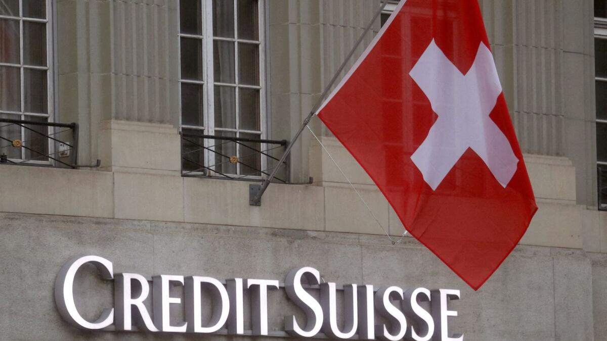 The Swiss flag flies above the Credit Suisse logo in Bern, Switzerland.  - Reuters