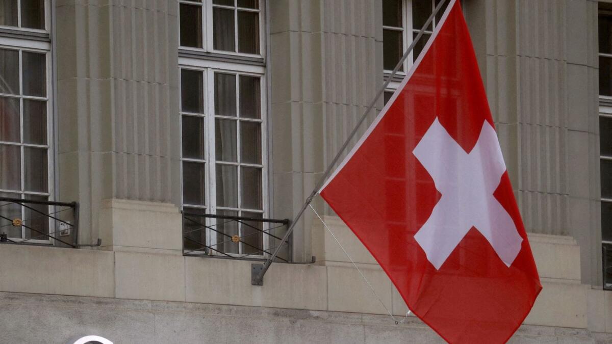 Switzerland's national flag flies above a logo of Credit Suisse in Bern, Switzerland. — Reuters