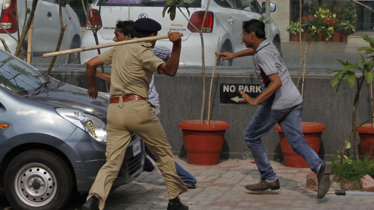 An Indian policeman uses a baton to disperse protesters during a clash between two groups in Ahmadabad, India. 