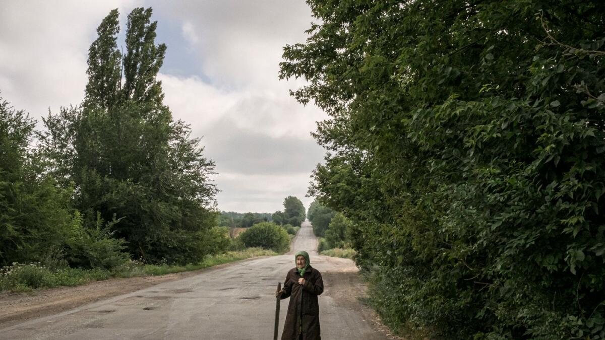 An elderly Ukrainian villager walks along a road on the outskirts of Dibrova on July 23, 2022.  (Mauricio Lima/The New York Times)