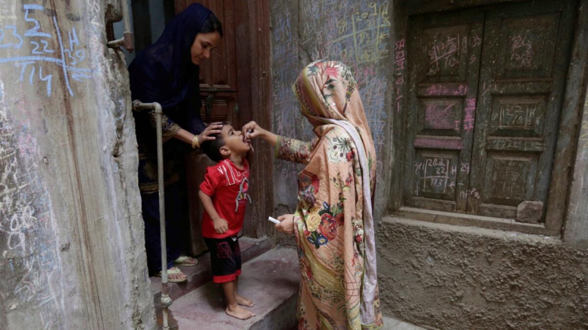 A health worker gives a polio vaccine to a child in a neighborhood of Lahore. — AP