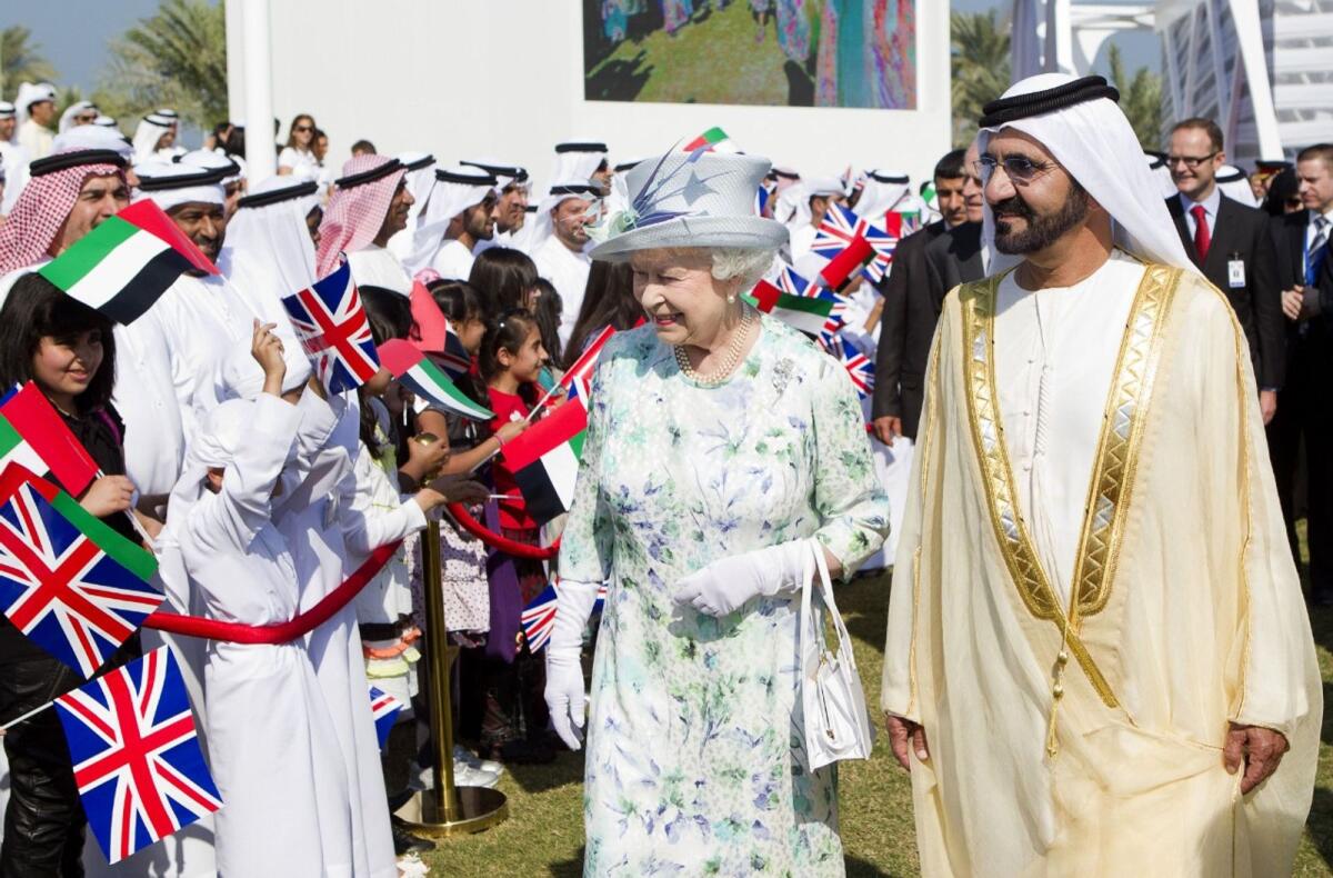 Dubai Ruler Sheikh Mohammed accompanies Queen Elizabeth as she smiles at residents lining up to get a glimpse of her.