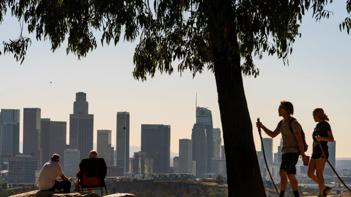 Albert Maghbouleh, far left, and Miles Santamour, 89, with Amigos de Jaibalito Foundation (ADJ) share lunch outdoors guarding social distancing, overlooking the skyline of Los Angeles on Jan. 11, 2021. -- AP