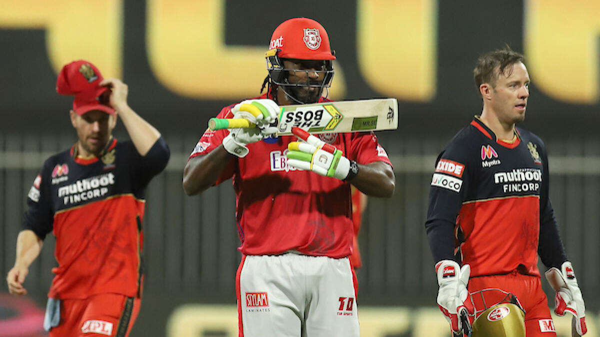 Kings XI Punjab's Chris Gayle (centre) points to his bat after scoring a half-century against Royals Challengers Bangalore in Sharjah on Thursday. - BCCI/IPL