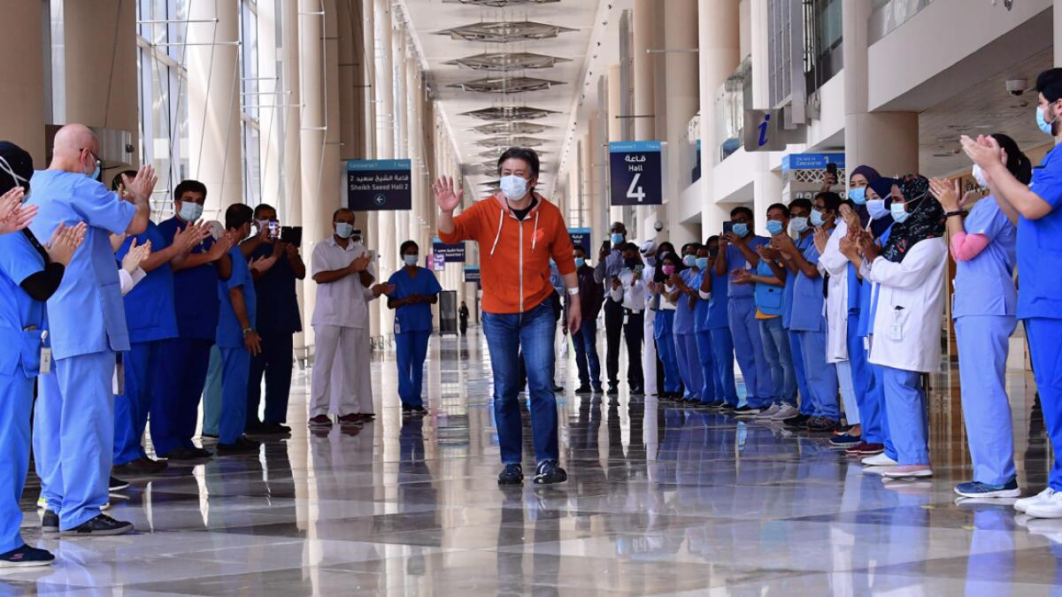 Hiroaki Fujita from Japan, the last patient at the temporary Covid-19 hospital built in downtown Dubai in the United Arab Emirates, greets nurses and doctors as he leaves the facility. Photo: AFP