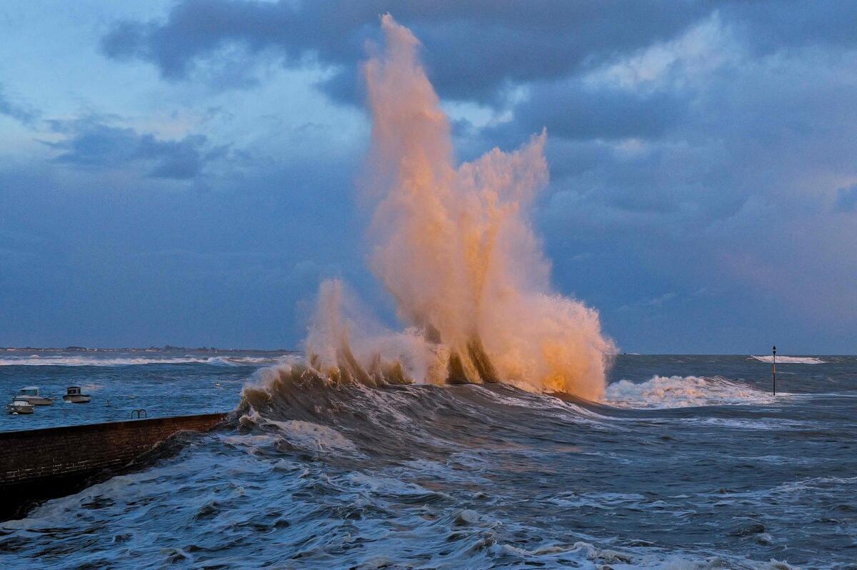 A wave crashes on a dyke in Lomener, western France. — AFP