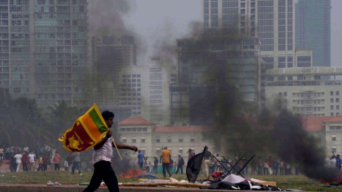 A Sri Lankan government supporter carries a national flag after attacking the anti-government protesters outside president's office in Colombo. — AP