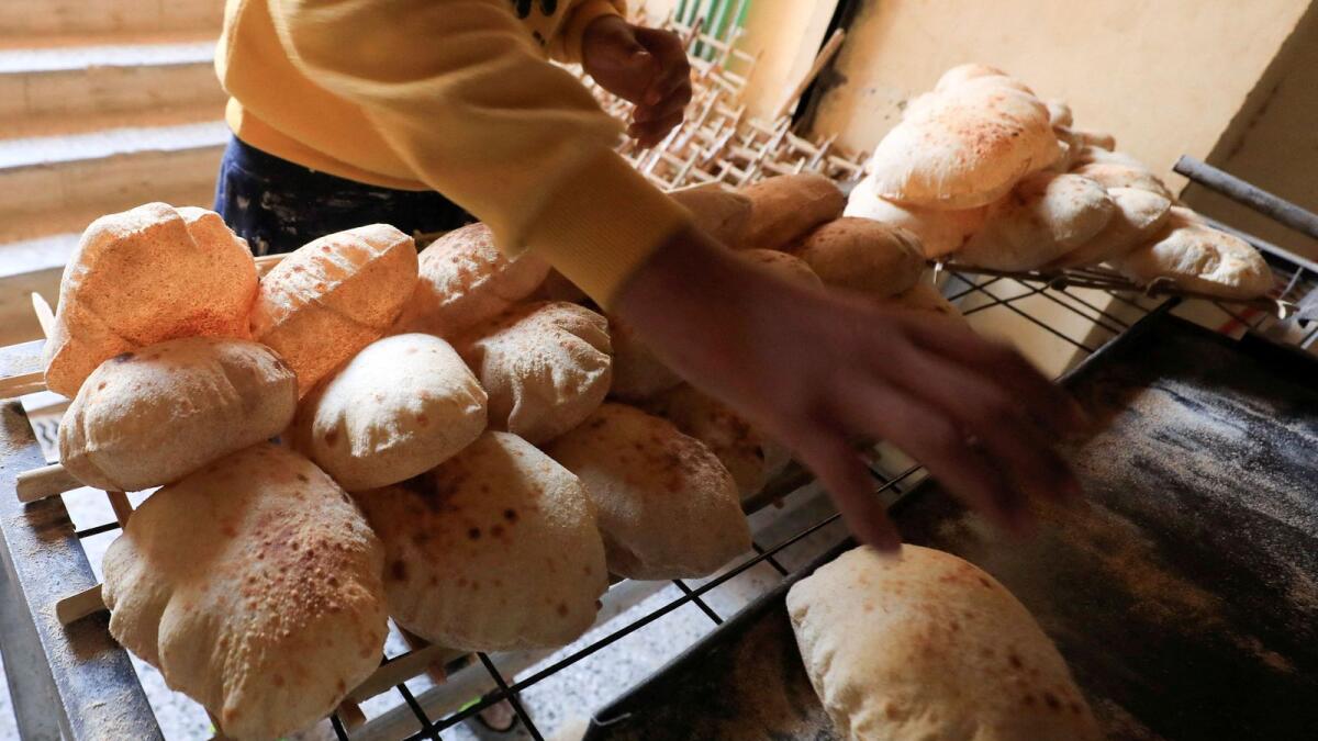 An Egyptian worker removes loaves of bread from the oven at a bakery in Cairo's southeastern Mokattam district. — Reuters file
