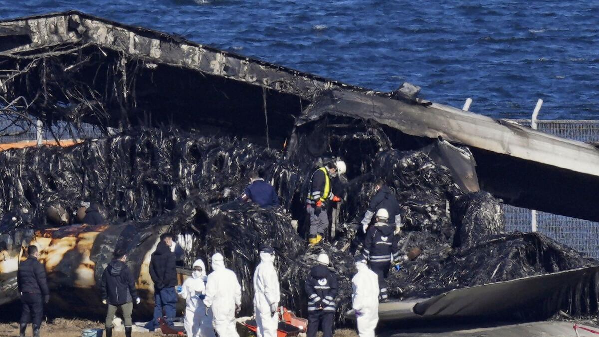 Officials investigate the wreckage of Japan Airlines plane at Haneda airport on Thursday in Tokyo. — AP