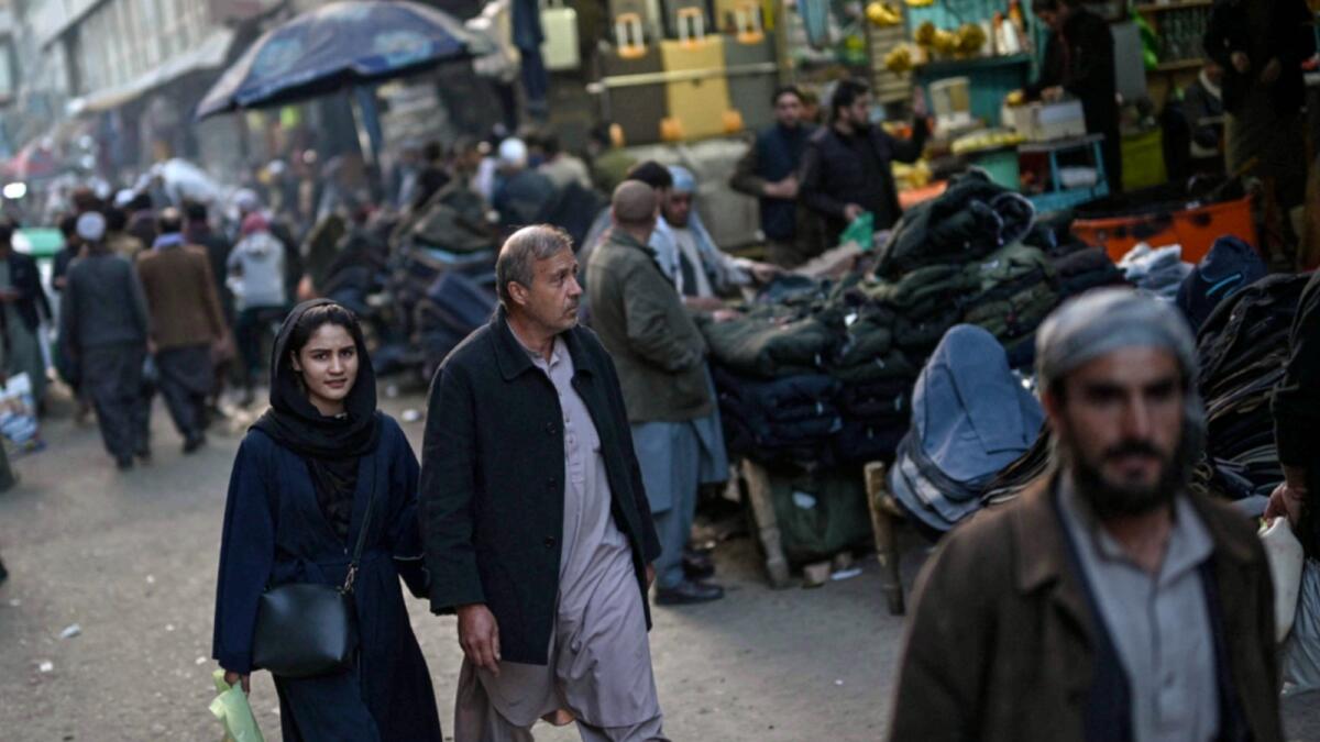 Afghan people walk through a street along a market in Kabul. — AFP