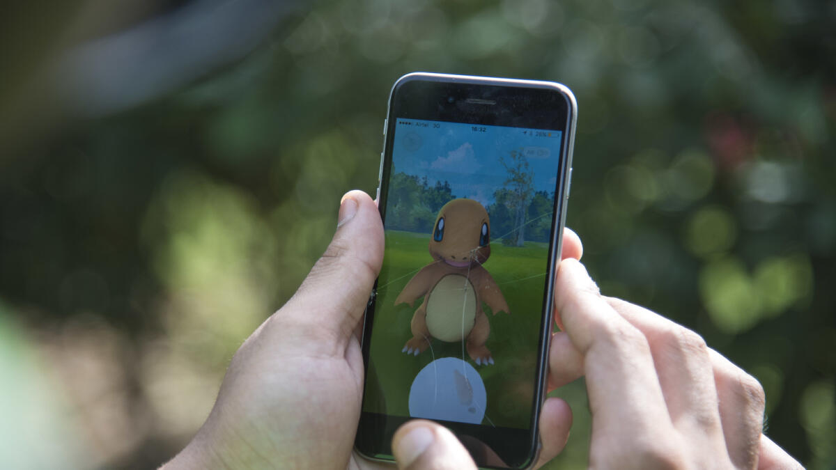 In this Friday, July 22, 2016 photo, a Pokemon Go player attempts to catch Charmander, one of Pokemon's most iconic creature, in New Delhi, India. 'Pokemon Go,' the highly addictive online game, has landed in India and thousands are out searching for pokemon characters as the mania spreads. Although it has not been launched officially in India, the augmented-reality-based game has caught on, with fans also using virtual private networks (VPNs) to change their locations and catch pokemons in New York and London while sitting in their Indian homes. (AP Photo/Thomas Cytrynowicz)