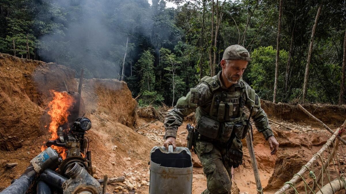 Felipe Finger, the head of Brazil’s environmental special forces team, burning a water pump at an illegal mine in the Yanomami Indigenous territory of Brazil, on Feb. 24, 2023. An explosion of illegal mining in this vast swath of the Amazon has created a humanitarian crisis for the Yanomami people, cutting their food supplies, spreading malaria and, in some cases, threatening the Yanomamis with violence, according to government scientists and officials. (Victor Moriyama/The New York Times)