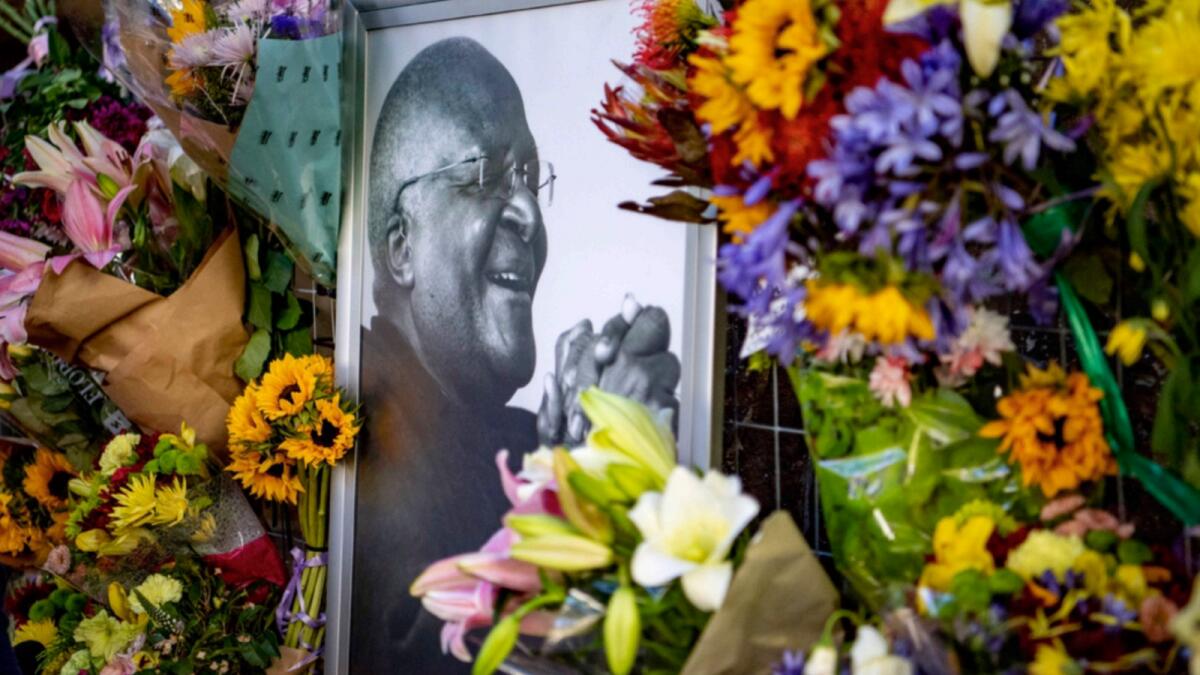Flowers surround a portrait of former Anglican Archbishop Desmond Tutu outside St. George's Catherdral in Cape Town. — AP