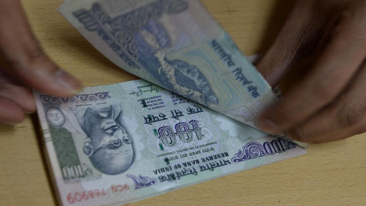 A bank staff counts Indian 100 rupee notes. — AFP