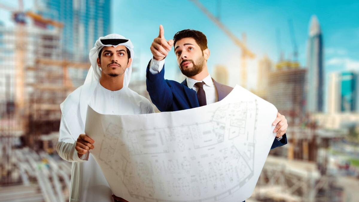 Pretty architect is explaining to Arab builders the plan of construction. The foreman pointing at building with seriousness.