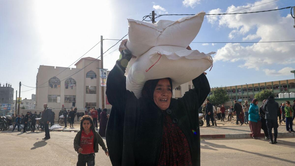 Palestinians receive bags of flour at the United Nations Relief and Works Agency for Palestine Refugees (UNRWA) distribution centre in the Rafah refugee camp in the southern Gaza Strip. — AFP